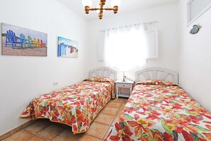 Ein Schlafzimmer mit zwei Betten, einem Nachttisch, einer Deckenleuchte und zwei Wandbildern.