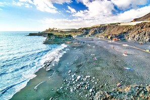 Ein Strand mit felsigem Gelände und freiem Blick auf den Ozean.