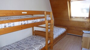 Ein Stockbett mit gemusterten Betttextilien in einem Zimmer mit Holzwänden und einem Fenster.