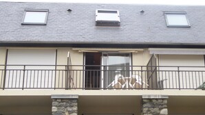 Ein zweistöckiges Gebäude mit Balkon, Schiebeglastür und einem kleinen Fenster im Obergeschoss.