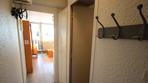 Un pasillo con un perchero, un banco de madera y una puerta que da a otra habitación.