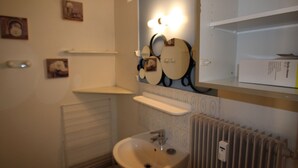 Un baño con lavamanos, espejo y radiador.