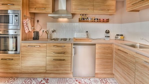A modern kitchen with wooden cabinets, stainless steel appliances, and a built-in dishwasher. - Stunning Renovated Mountain-Style 2BR+Cabin Apt near Village Center, Sleeps 6 (Les Gets)