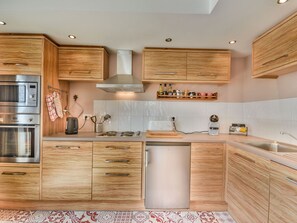 Eine moderne Küche mit Holzschränken, Edelstahlgeräten und einem eingebauten Geschirrspüler.