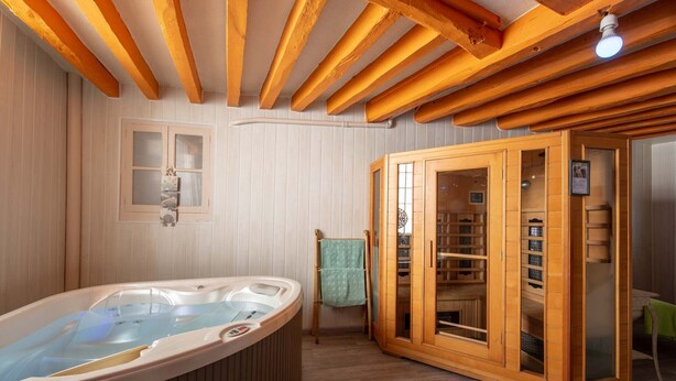 Um quarto de spa com hidromassagem, armários de madeira e teto de madeira.