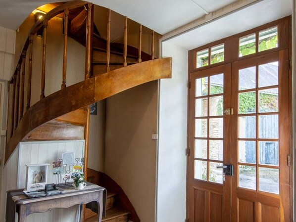 A wooden staircase with a curved design leading to a landing. A wooden door with glass panels is visible to the right.