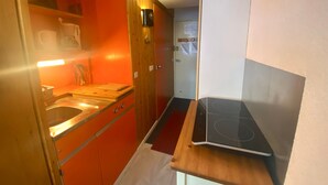 Een kleine keuken met een houten aanrecht, een inbouwoven en een klein spoelbakje.