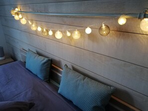 A bed with a headboard, pillows, and a string of lights.