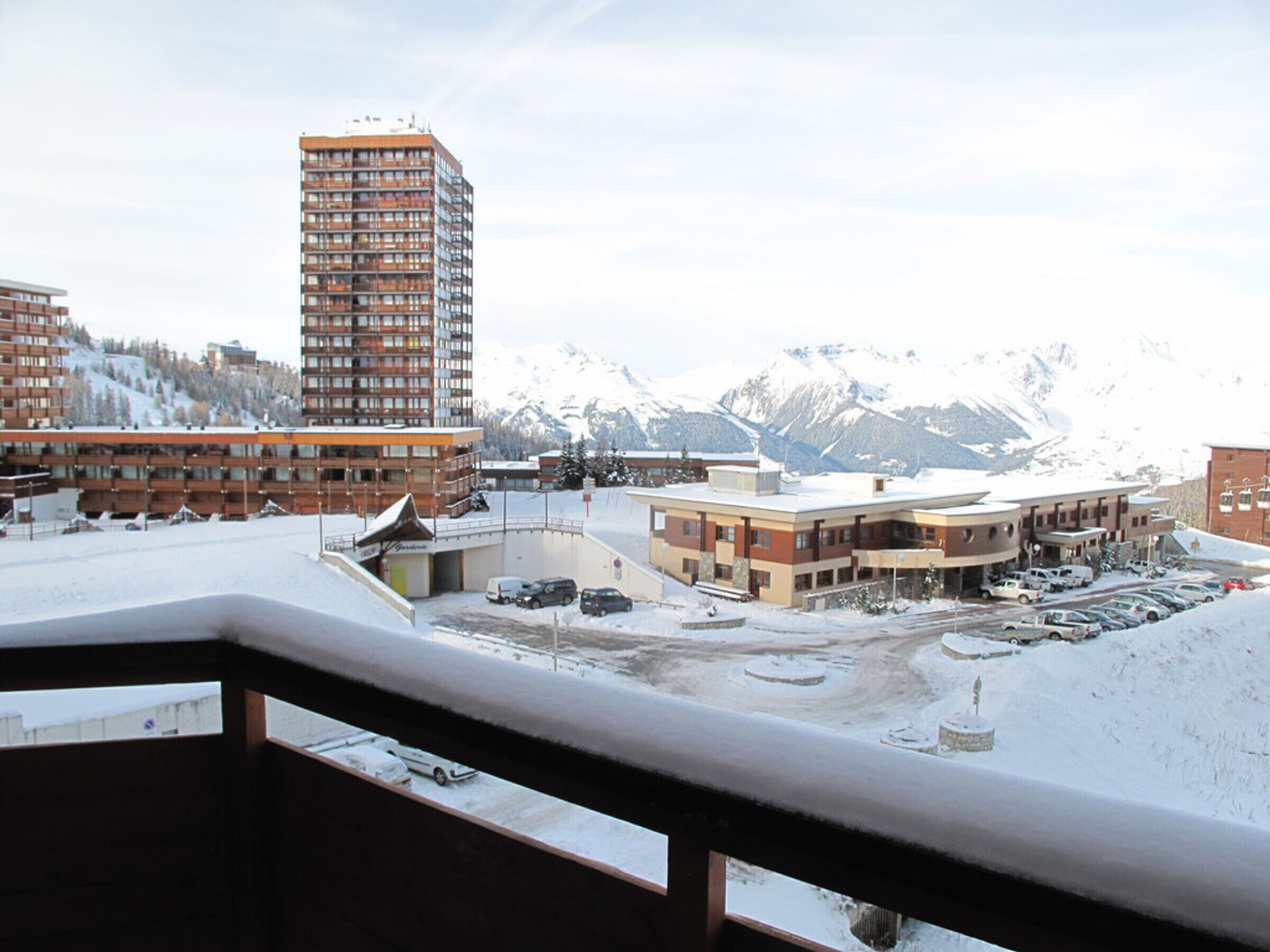 Un hotel con varias construcciones, un estacionamiento y una montaña nevada al fondo.