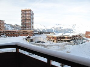 A hotel with multiple buildings, a parking lot, and a snowy mountain backdrop.