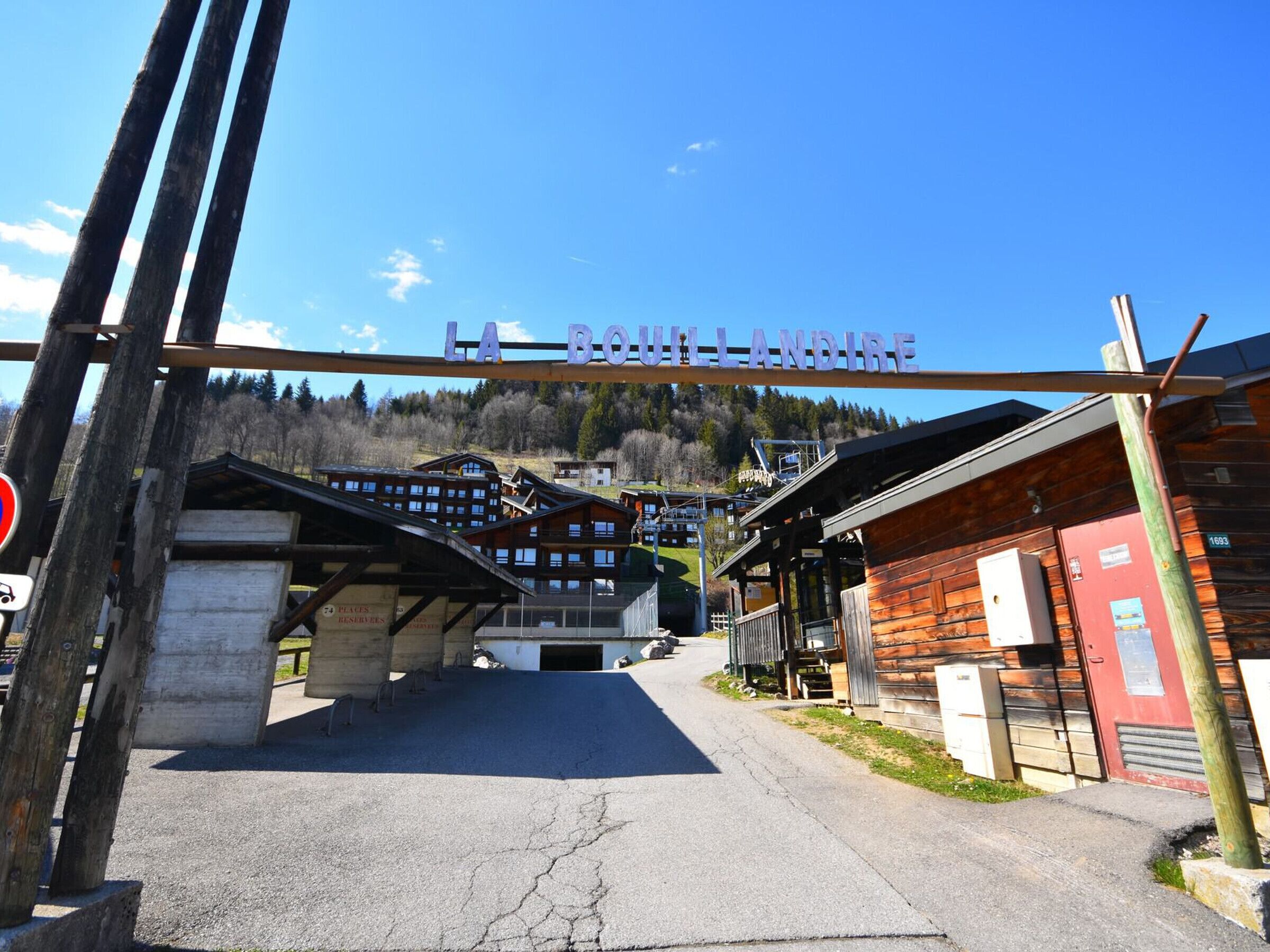 Eingangsbereich eines Skigebiets mit Holzbauten und blauem Himmel.