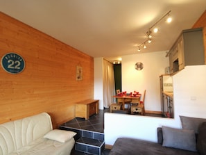 Uma sala de estar acolhedora com sofá, mesa de jantar e cadeiras, e área de cozinha.