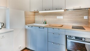 Een moderne keuken met witte kasten, een houten aanrecht, een spoelbak, een snijplank en een vaatwasser.