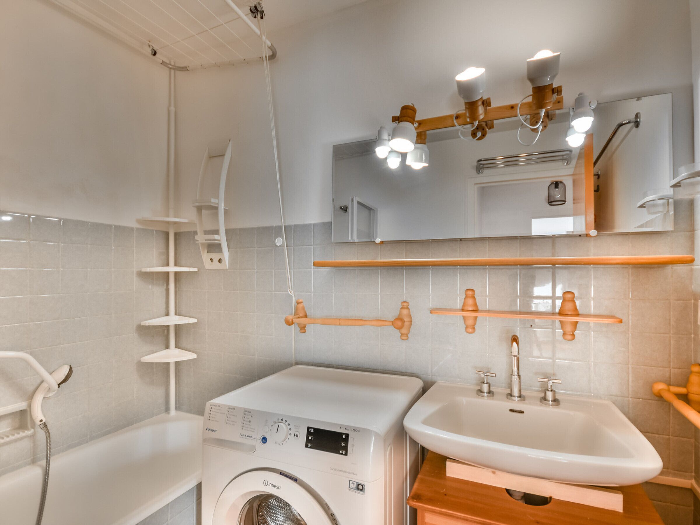 A modern bathroom with a washing machine, a sink, and a shower.