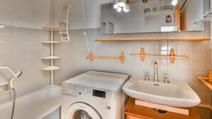Een moderne badkamer met een wasmachine, een wastafel en een douche.