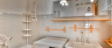 A modern bathroom with a washing machine, a sink, and a shower.