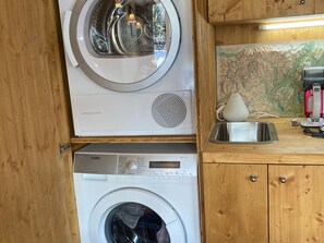Une cuisine compacte équipée d’un lave-linge, d’un lave-vaisselle à nettoyage automatique et d’un évier.