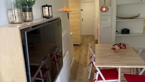 Una cucina compatta con un tavolo e sedie in legno, un piccolo angolo ristoro e una porta che dà su un'altra stanza.