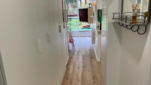 Un corridoio con pavimento in legno, una porta bianca e una piccola mensola con una statuetta di cervo.