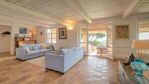 Ein geräumiges Wohnzimmer mit Klavier, zwei Sofas und einem Essbereich mit Tisch und Stühlen.
