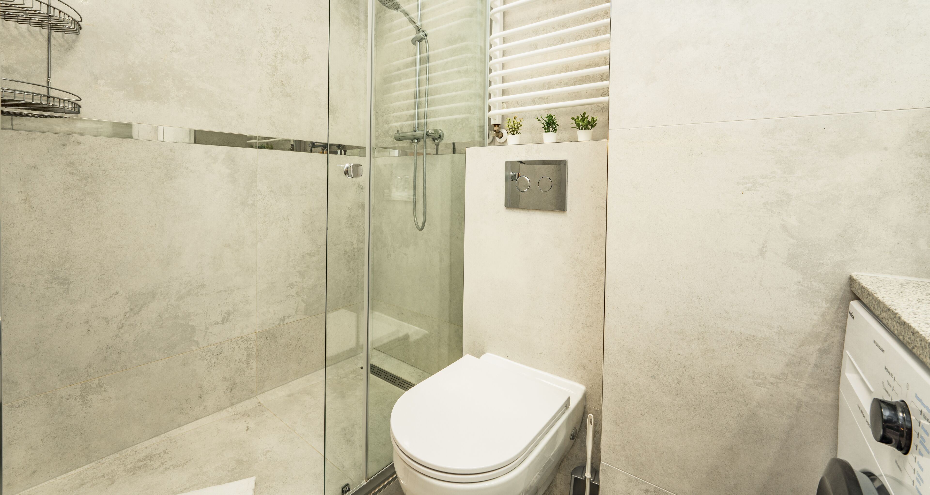 Een moderne badkamer met een douchecabine van glas, een toilet en een wasmachine.