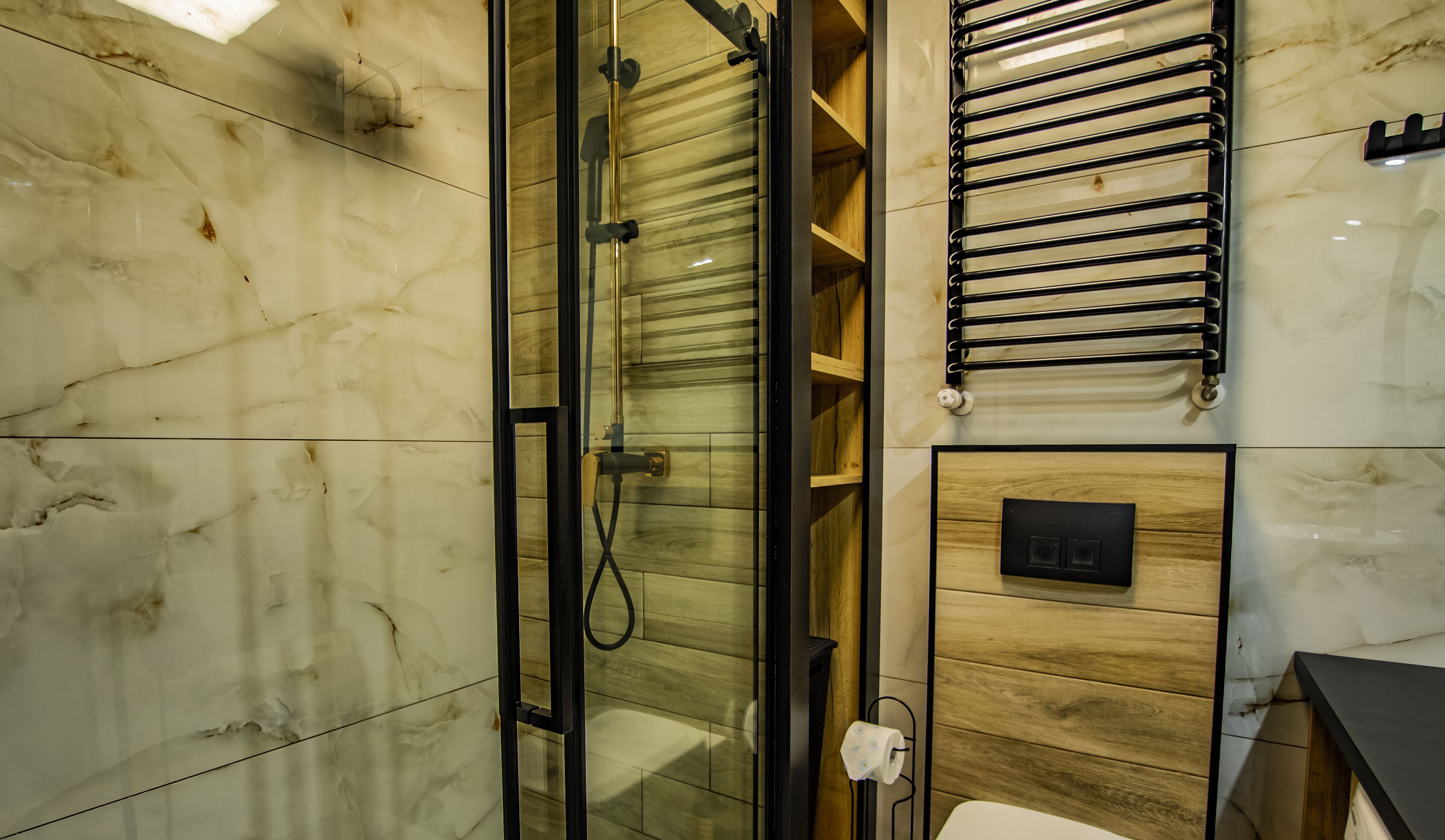 A bathroom with a glass-enclosed shower, marble walls, wooden paneling, and a towel rack.