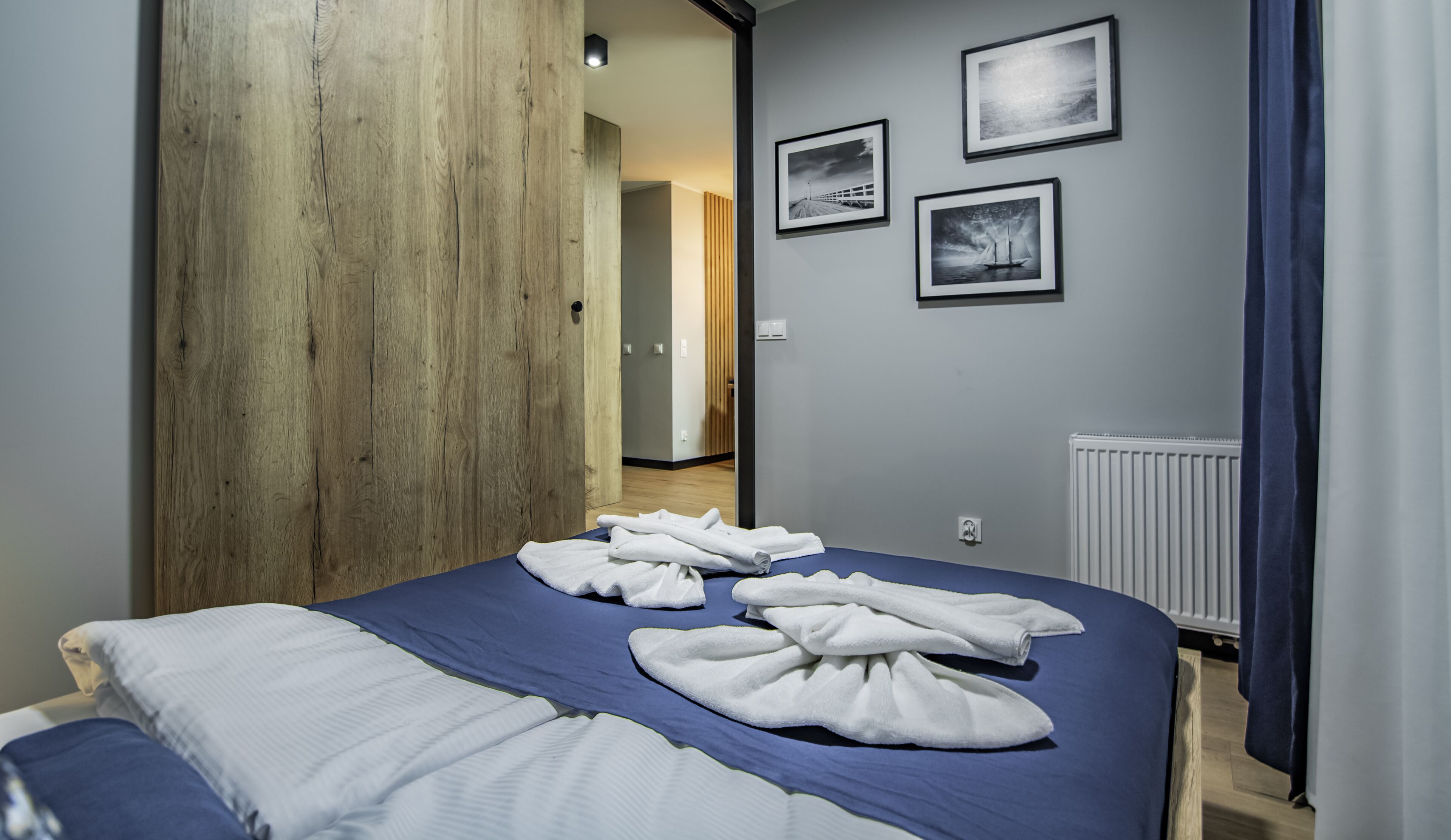 Una habitación de hotel con una cama grande, una puerta de madera y vista al pasillo.