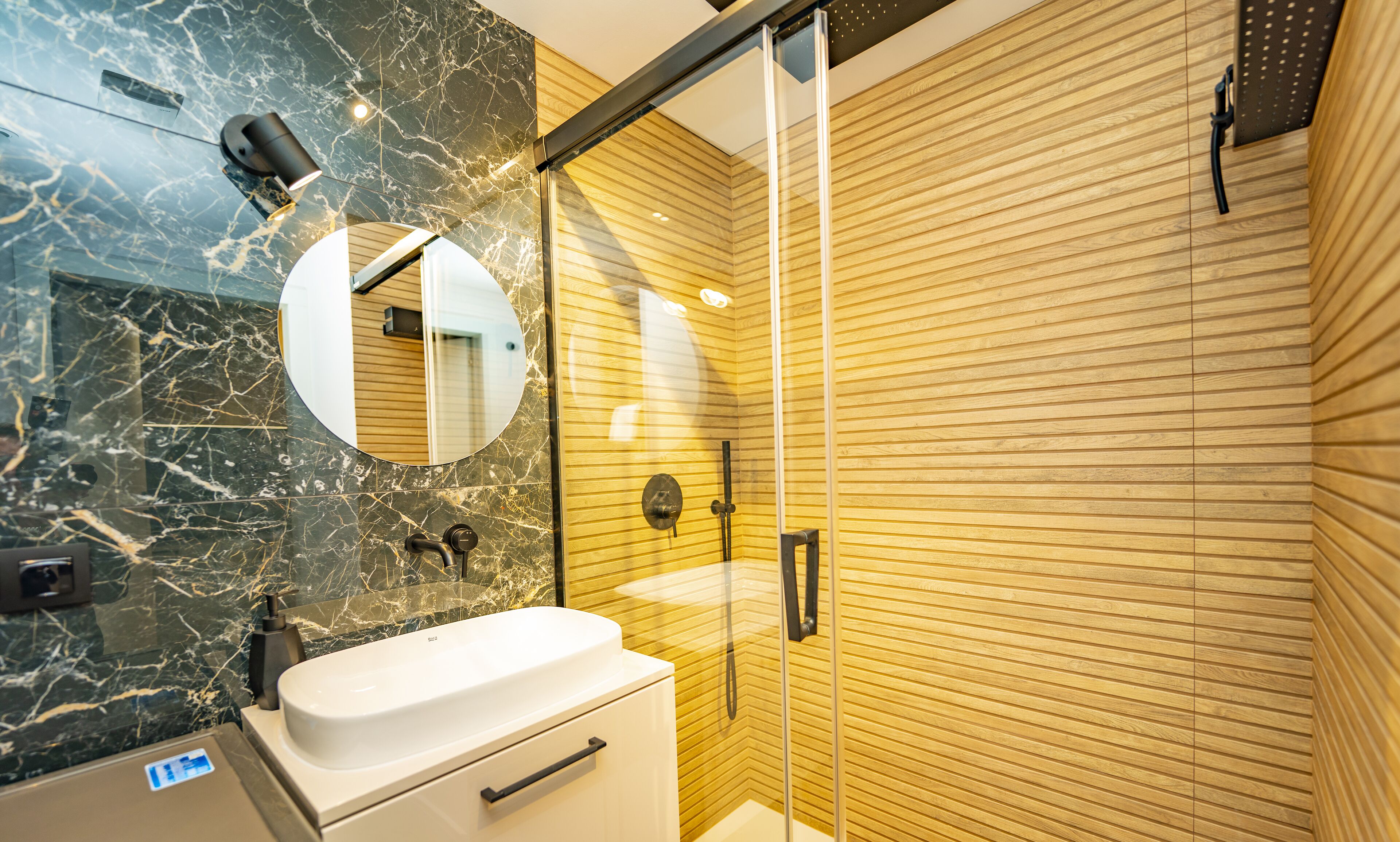 A modern bathroom with a marble vanity, a glass shower enclosure, and wooden paneling.