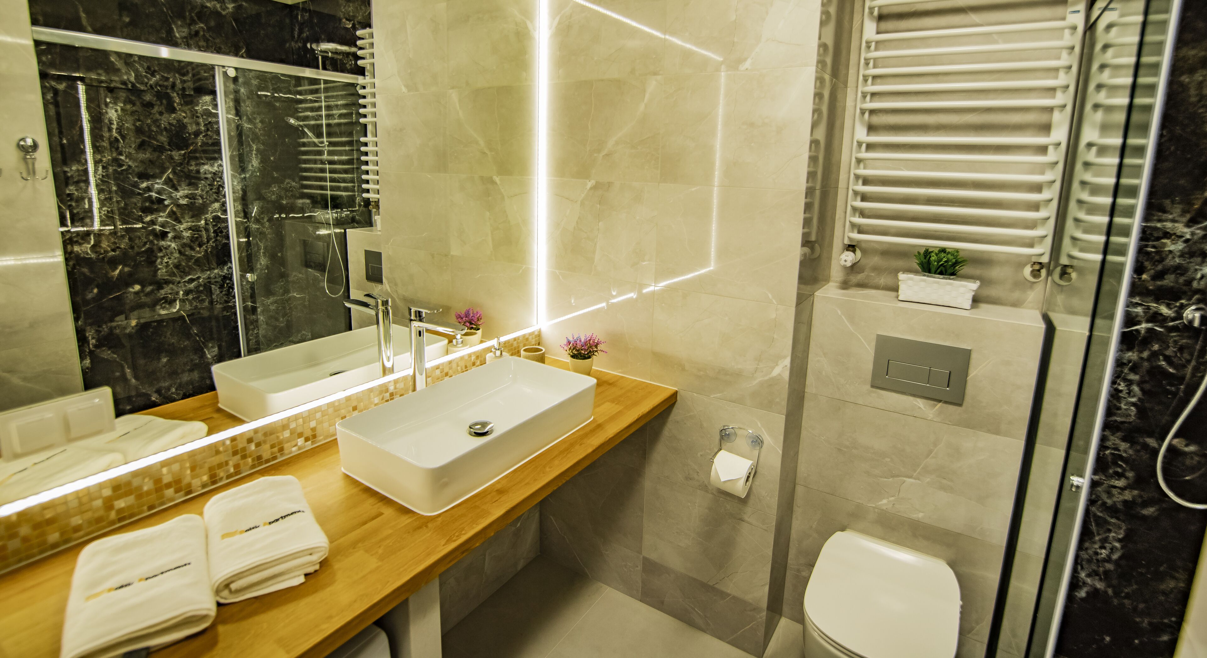 A modern bathroom with a large mirror, a sink, and a shower.