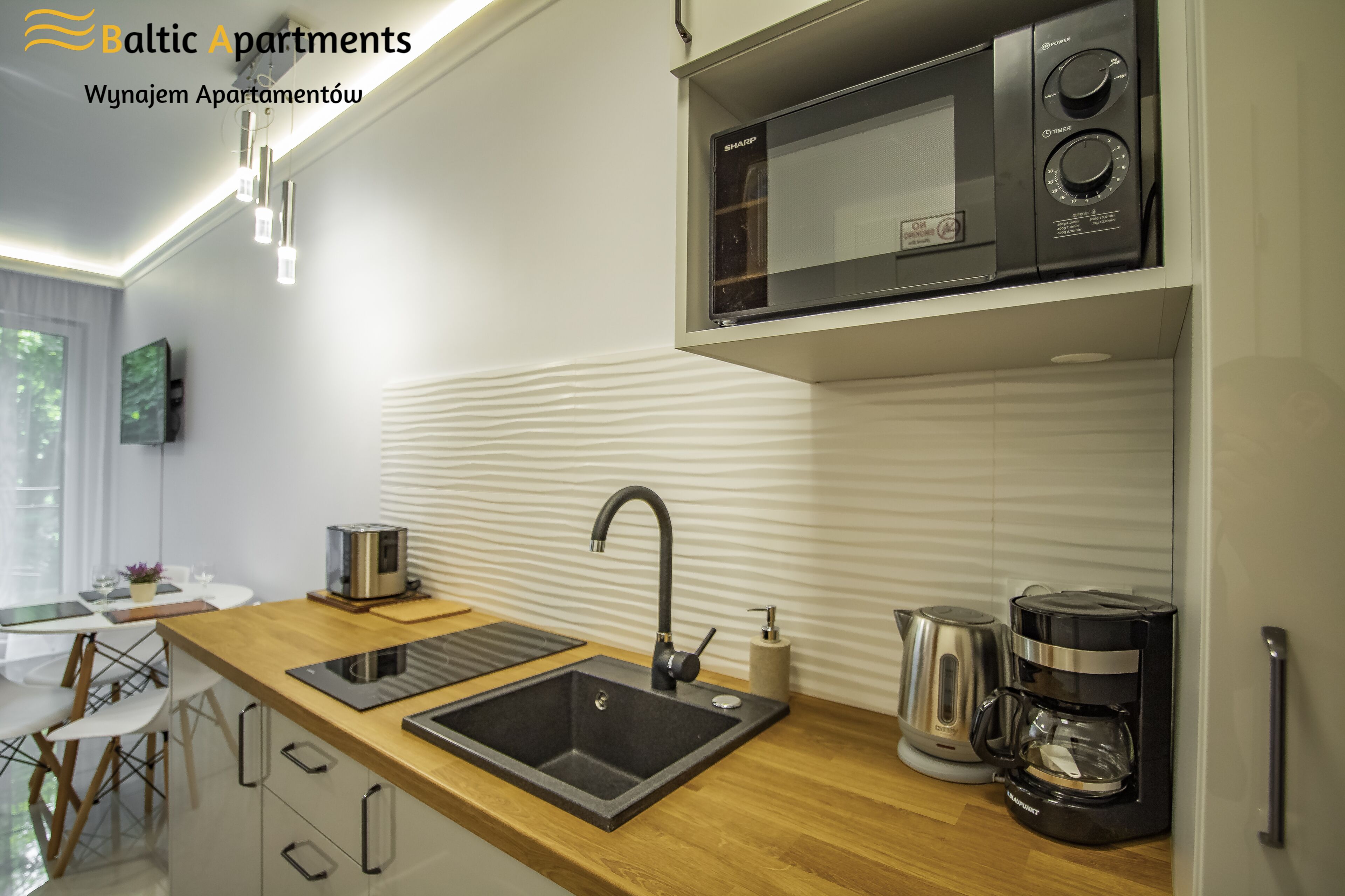 A modern kitchen with a wooden countertop, a built-in microwave, a coffee maker, and a sink.