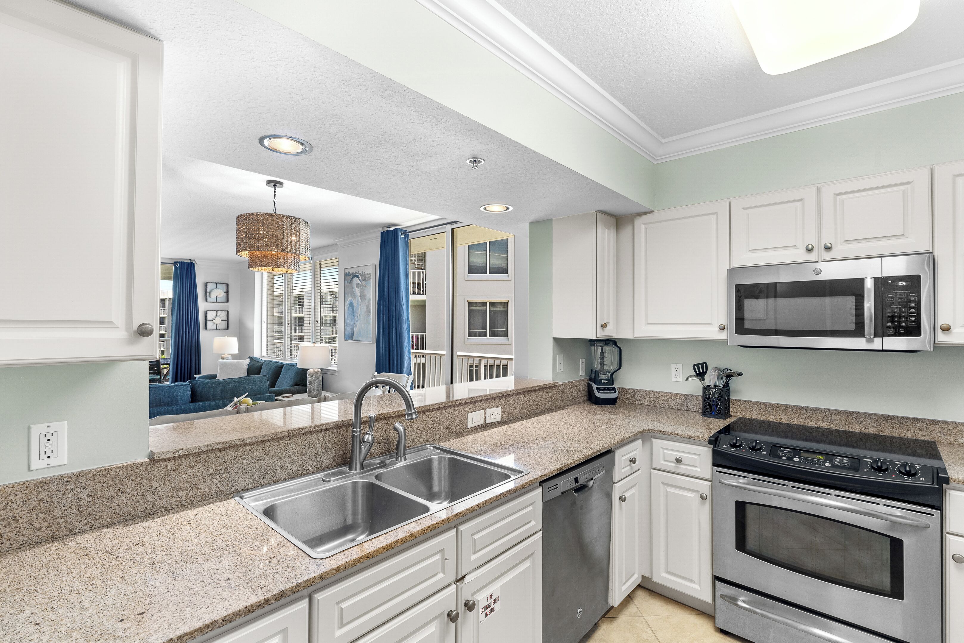 A modern kitchen with granite countertops, stainless steel appliances, and white cabinetry.