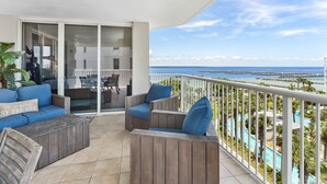 Un balcón con mobiliario de madera, vista al mar y zona de piscina.