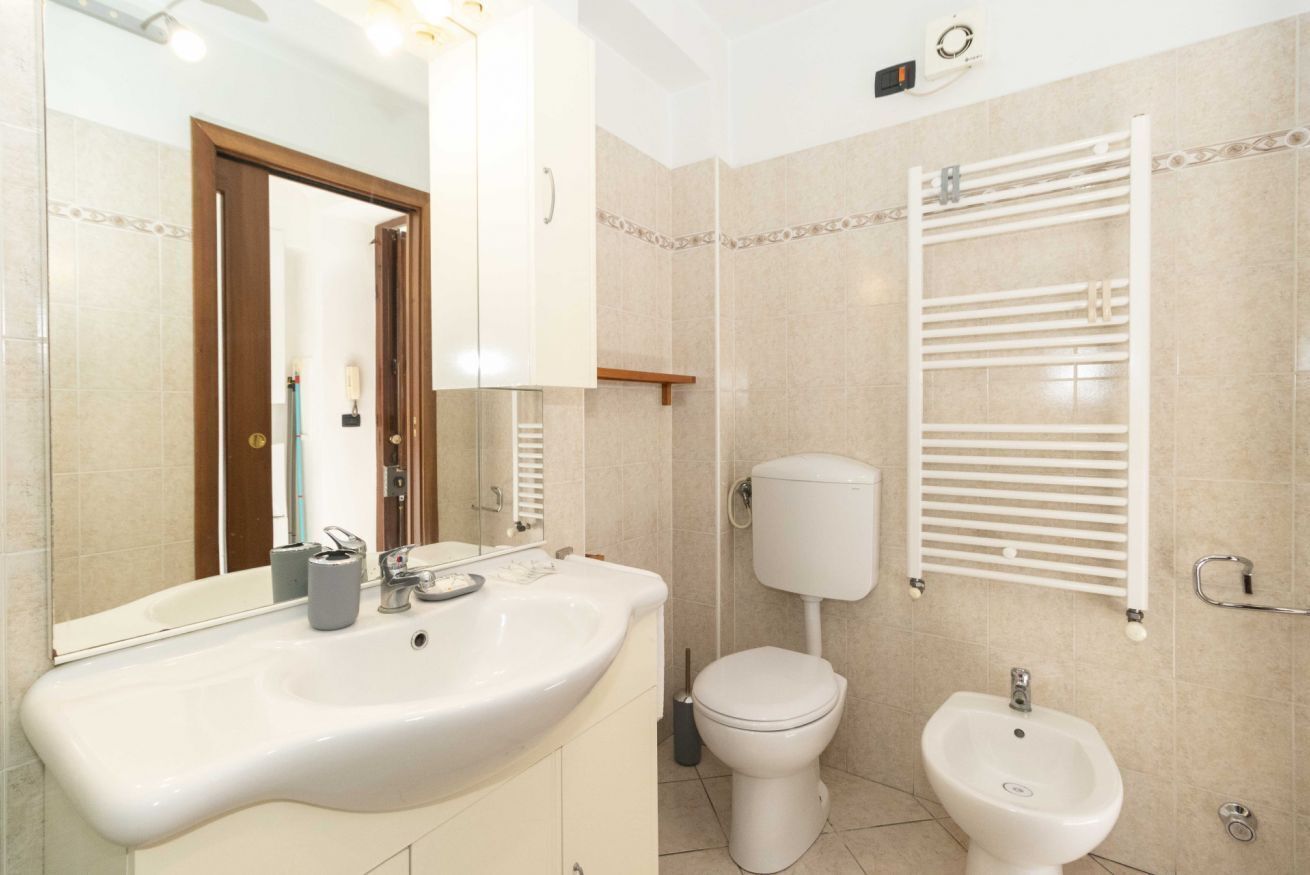 A bathroom with a sink, toilet, bidet, and towel rack.