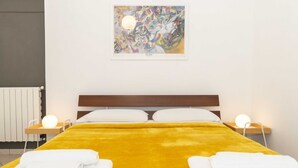 Une chambre d’hôtel avec un lit, des serviettes blanches, un tableau au mur et des lampes de chevet.