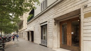 Rua com edifícios, calçada e motocicletas estacionadas.