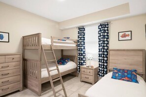 Habitación con literas, una escalera, mesitas de noche y una cama individual.