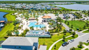 Vista aérea de un resort con piscina central, varias edificaciones y un lago.
