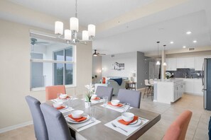 Una cocina moderna con armarios blancos, una isla central y un comedor con mesa para cuatro.