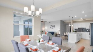 Una cocina moderna con armarios blancos, una isla central y un comedor con mesa para cuatro.