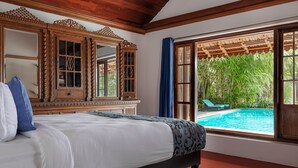 A bedroom with a large bed, wooden headboard, and a view of a swimming pool.