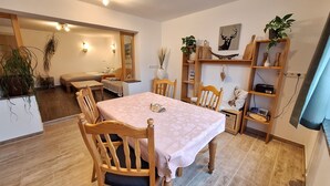 A dining area with a table and chairs, a bookshelf, and a mirror.