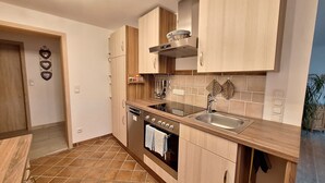 A modern kitchen with wooden cabinets, a built-in oven, a stovetop, and a sink.