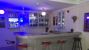 A bar area with a counter, stools, and shelves of bottles. - Animens Hotel Takoradi (Sekondi-Takoradi)