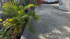 A gated entrance with a white van parked inside, surrounded by lush greenery and flowering plants. - Animens Hotel Takoradi (Sekondi-Takoradi)