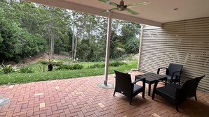 A covered patio with a brick floor, a ceiling fan, and outdoor furniture.