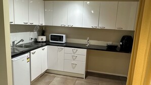 A modern kitchen with white cabinets, a black countertop, a microwave, a coffee maker, and a sink.