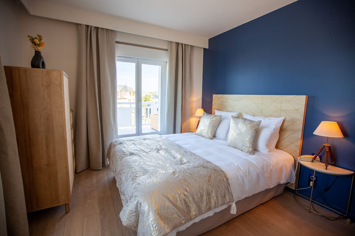 Een hotelkamer met een groot bed, een nachtkastje, een houten kledingkast en uitzicht buiten door een schuifdeur.