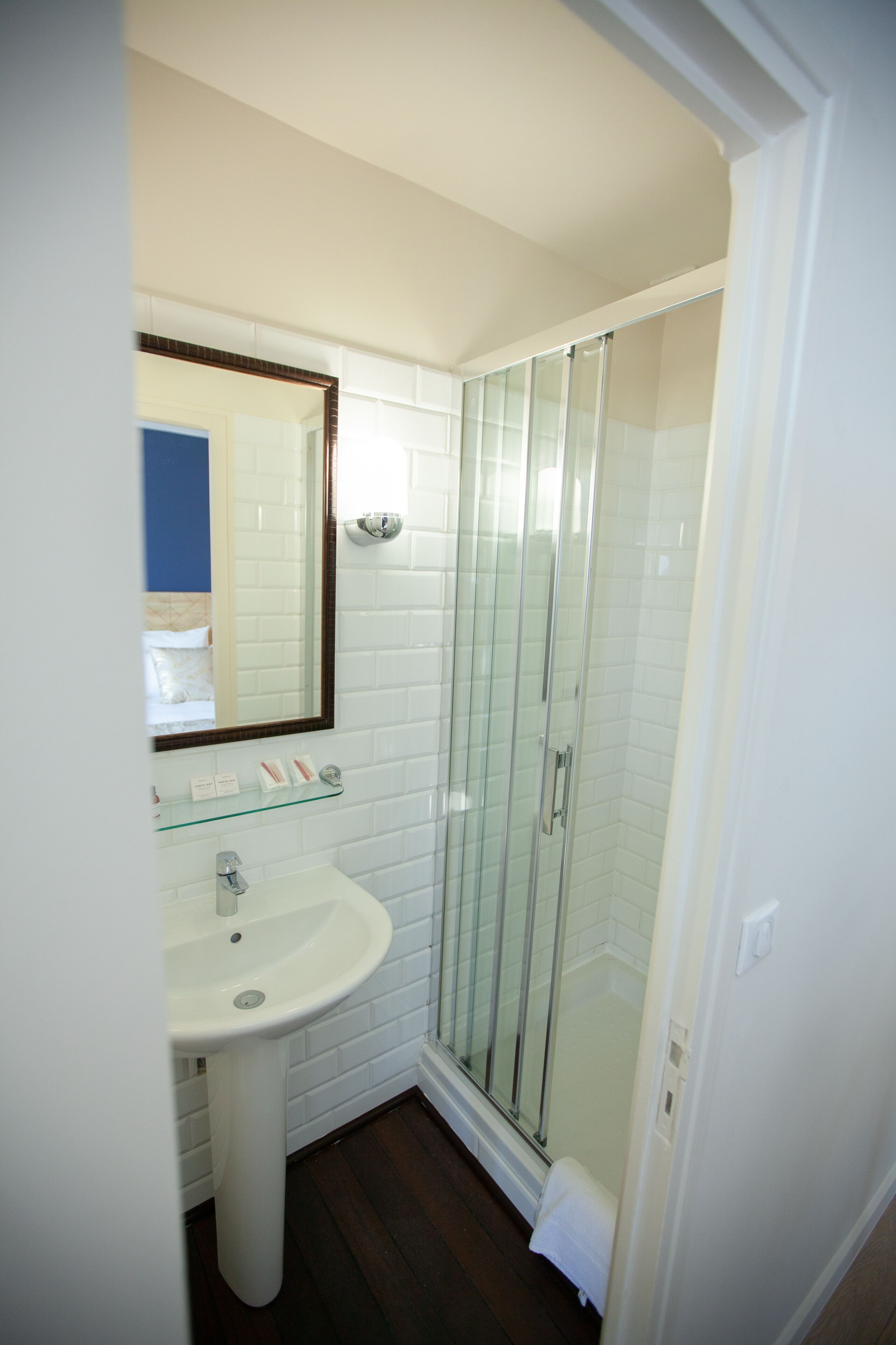 Une salle de bain avec une douche à parois de verre, un lavabo blanc et un miroir au-dessus du lavabo.