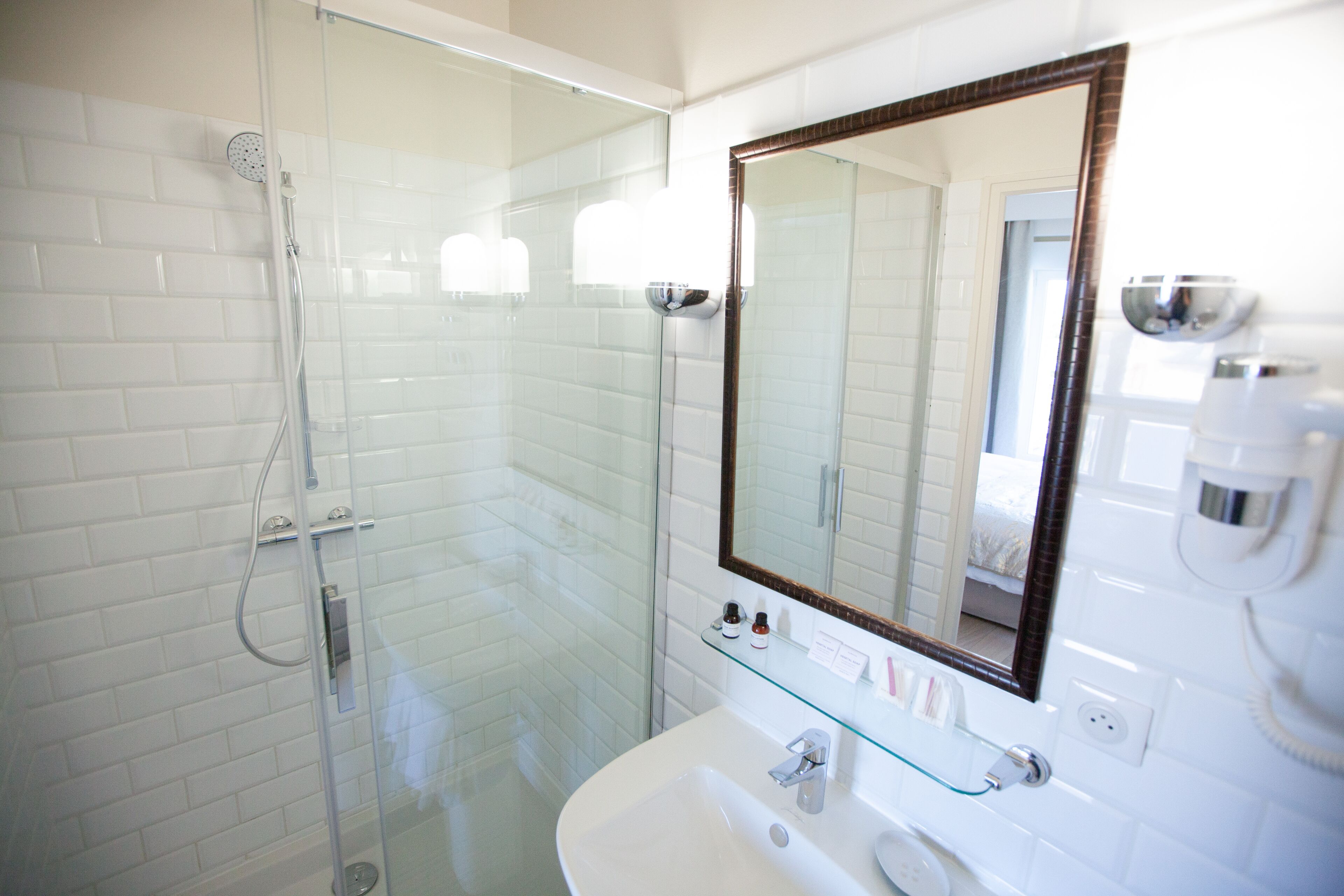 A modern bathroom with a glass-enclosed shower, a white sink, and a large mirror.