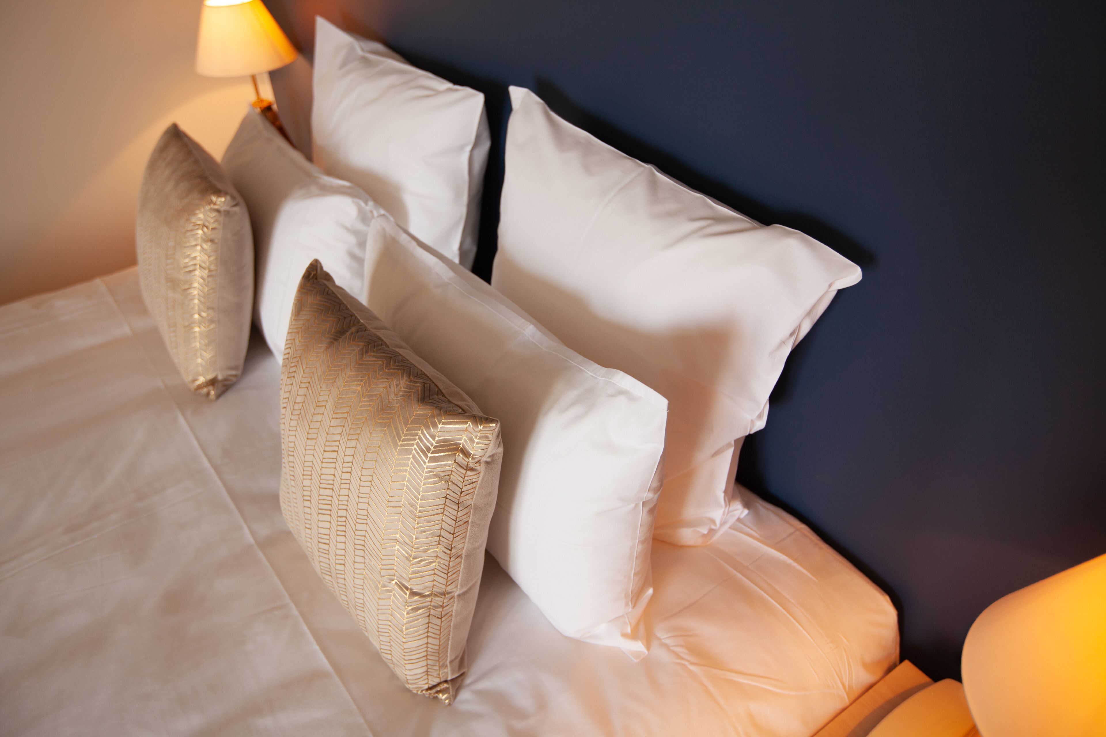 Un letto rifatto con lenzuola bianche e diversi cuscini decorativi.